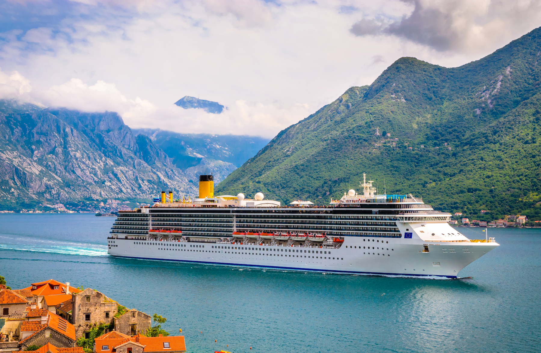 A large cruise ship is floating on top of a body of water surrounded by mountains.