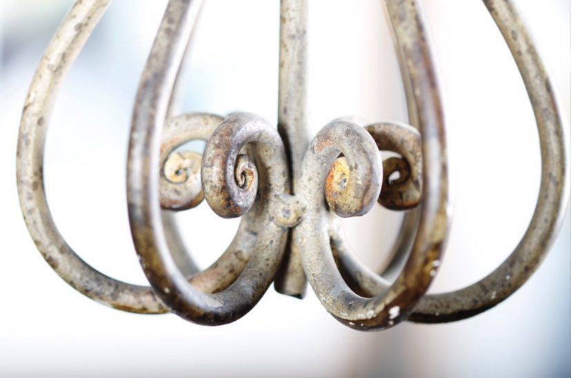 Rusty metal chandelier loops with decorative scrollwork on a white background