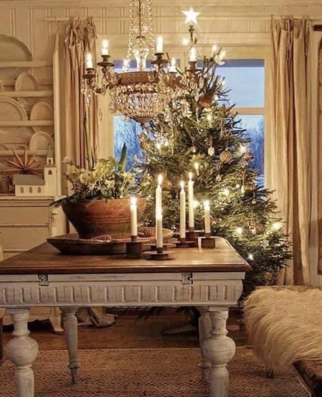 Cozy living room with a lit Christmas tree, chandelier, candles, and a rustic table centerpiece