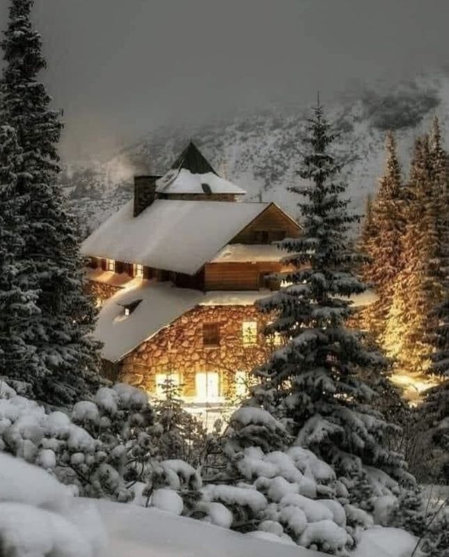Snow-covered cabin glowing warmly in a winter forest at dusk