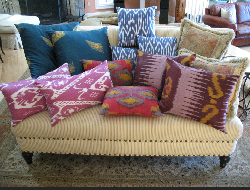 Colorful patterned pillows arranged on a cream sofa in a cozy living room
