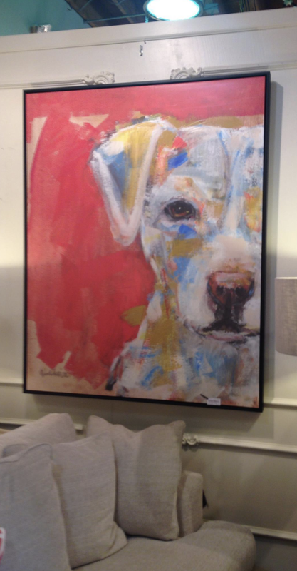 Abstract dog portrait in a black frame on a red wall above a light gray sofa.