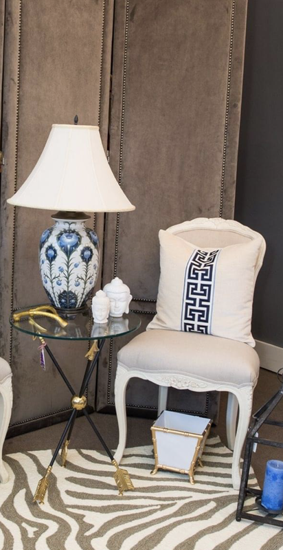 Elegant chair and side table with blue-and-white lamp and vase on a zebra-print rug in a styled room
