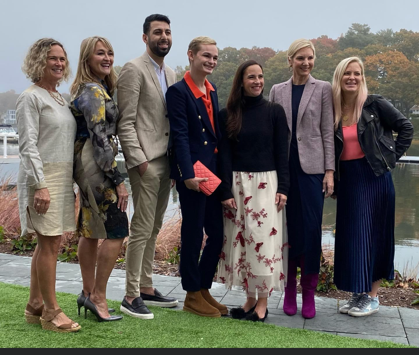 Seven people posing together outdoors on grass in formal and semi-formal attire