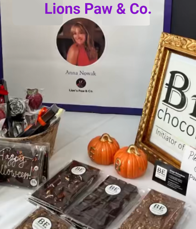 Lions Paw & Co. product display with chocolates, small pumpkins, and a business sign on a table