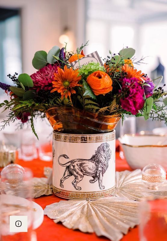 Colorful floral arrangement in a rooster-themed vase on a decorated table