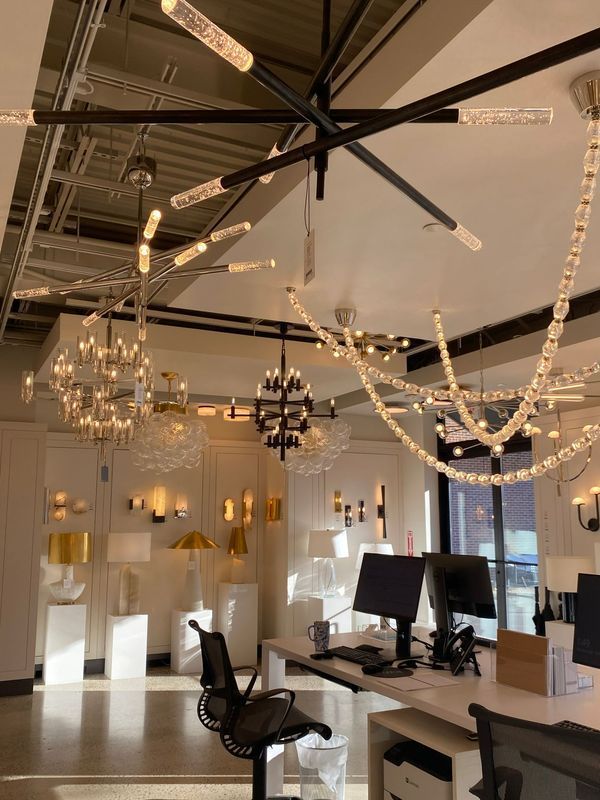 Modern office interior with tall ceilings, hanging lights, desks, and computer monitors