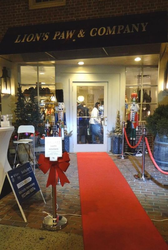 Storefront entrance with red carpet and velvet ropes at night, labeled “Lion’s Paw & Company.”