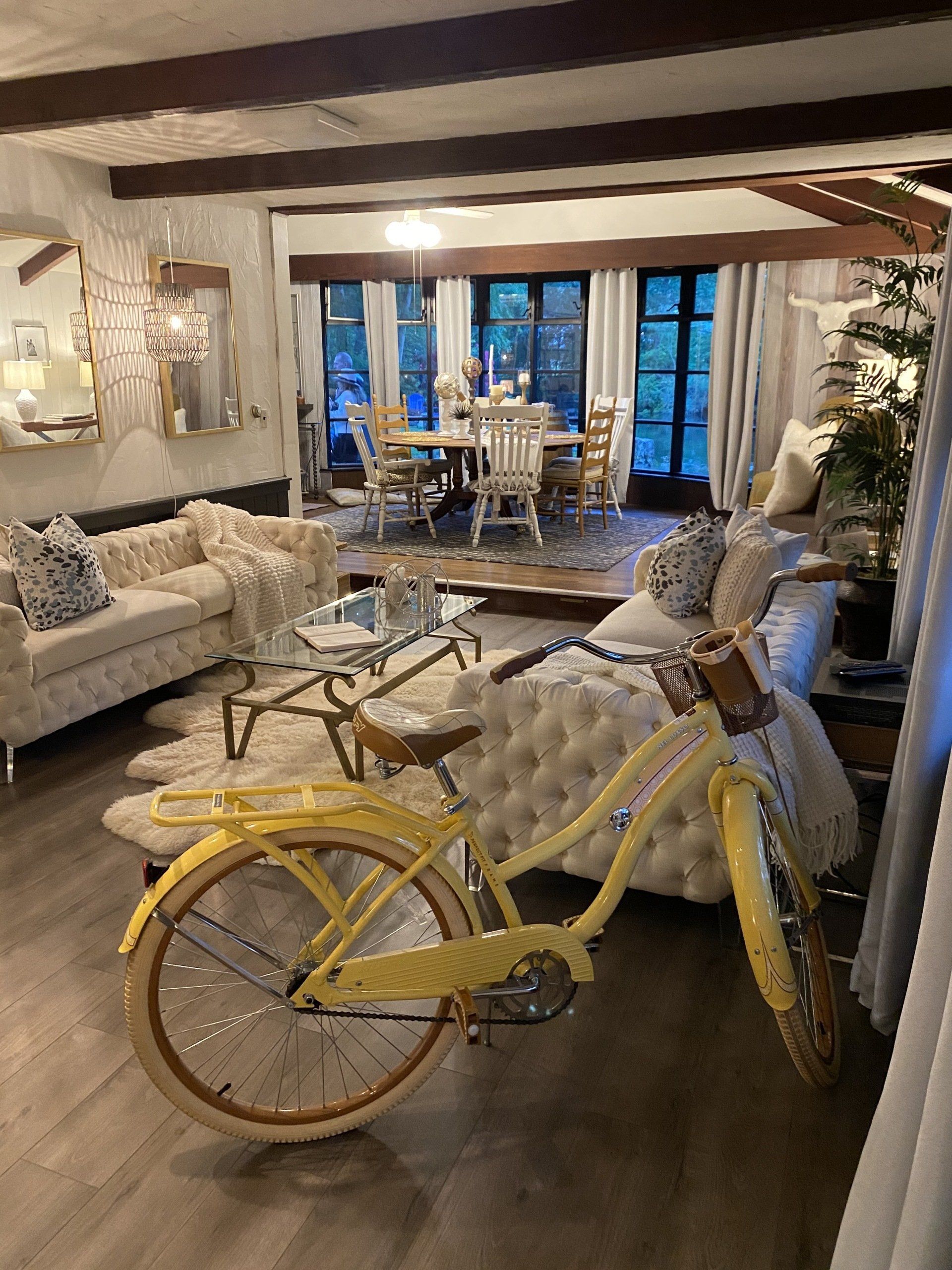 Yellow bicycle in a cozy living room with a dining area and large windows in the background Yellow bicycle in a cozy living room with a dining area and large windows in the background