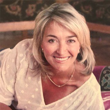 Smiling blonde woman reclining on a patterned sofa, wearing a light top. Smiling blonde woman reclining on a patterned sofa, wearing a light top.