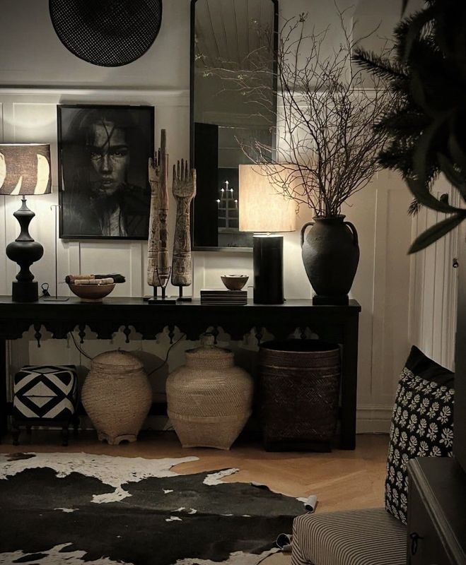 Stylish dark living room with abstract art, lamps, vases, and a cowhide rug lit by warm ambient light