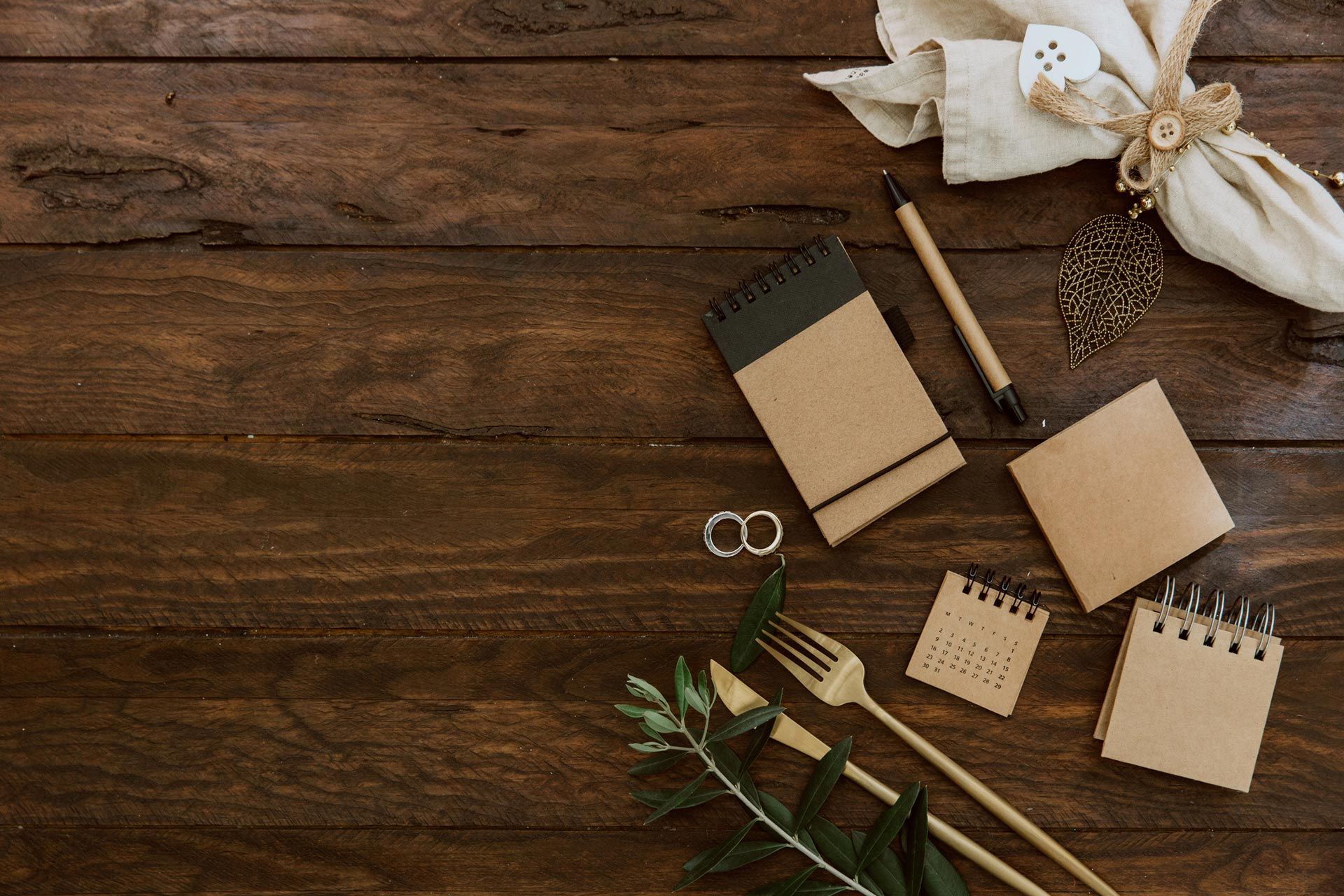 Flat-lay of rustic notebooks, pencils, scissors, and greenery on a wooden table Flat-lay of rustic notebooks, pencils, scissors, and greenery on a wooden table