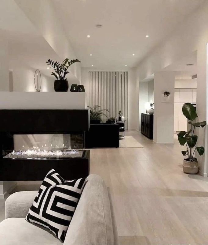 Modern minimalist living room with white walls, black fireplace, striped chairs, and indoor plants