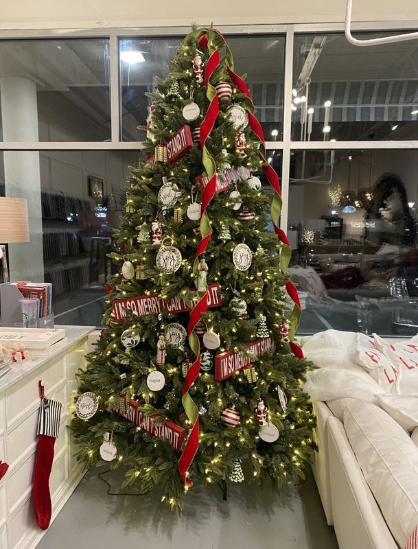 Decorated Christmas tree with red and white ornaments in a living room near a window and sofa