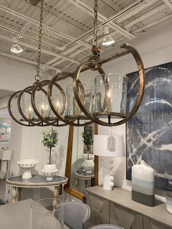 Industrial-style hanging chandelier with bronze rings over a showroom table and decor displays