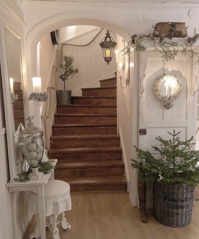 Elegant foyer with a staircase, hanging lanterns, and potted greenery in warm neutral tones