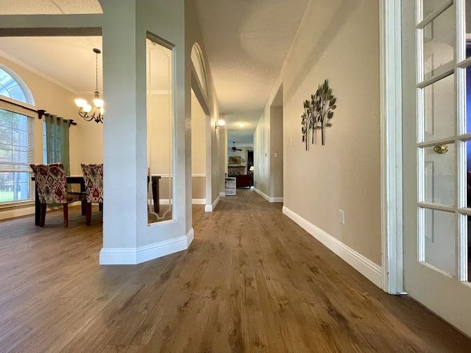 A hallway in a house with hardwood floors and a dining room.
