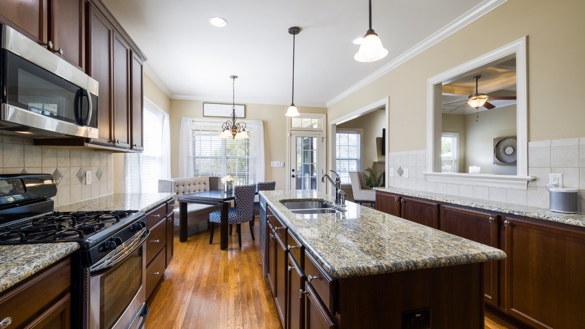 Modern kitchen with dark wood cabinets, granite island, stainless appliances, and hardwood floors