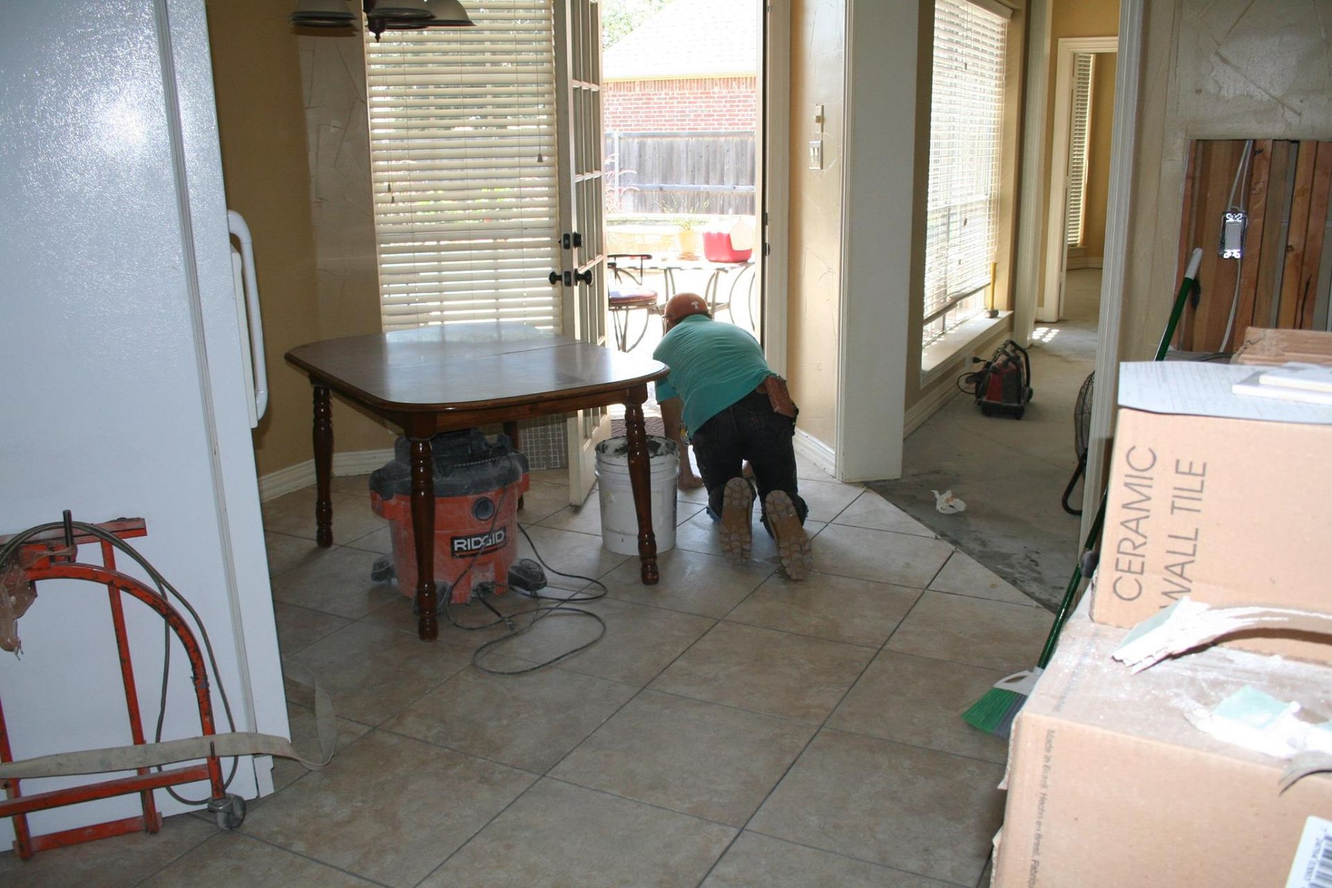 A man cleaning a table with a box that says ceramic on it