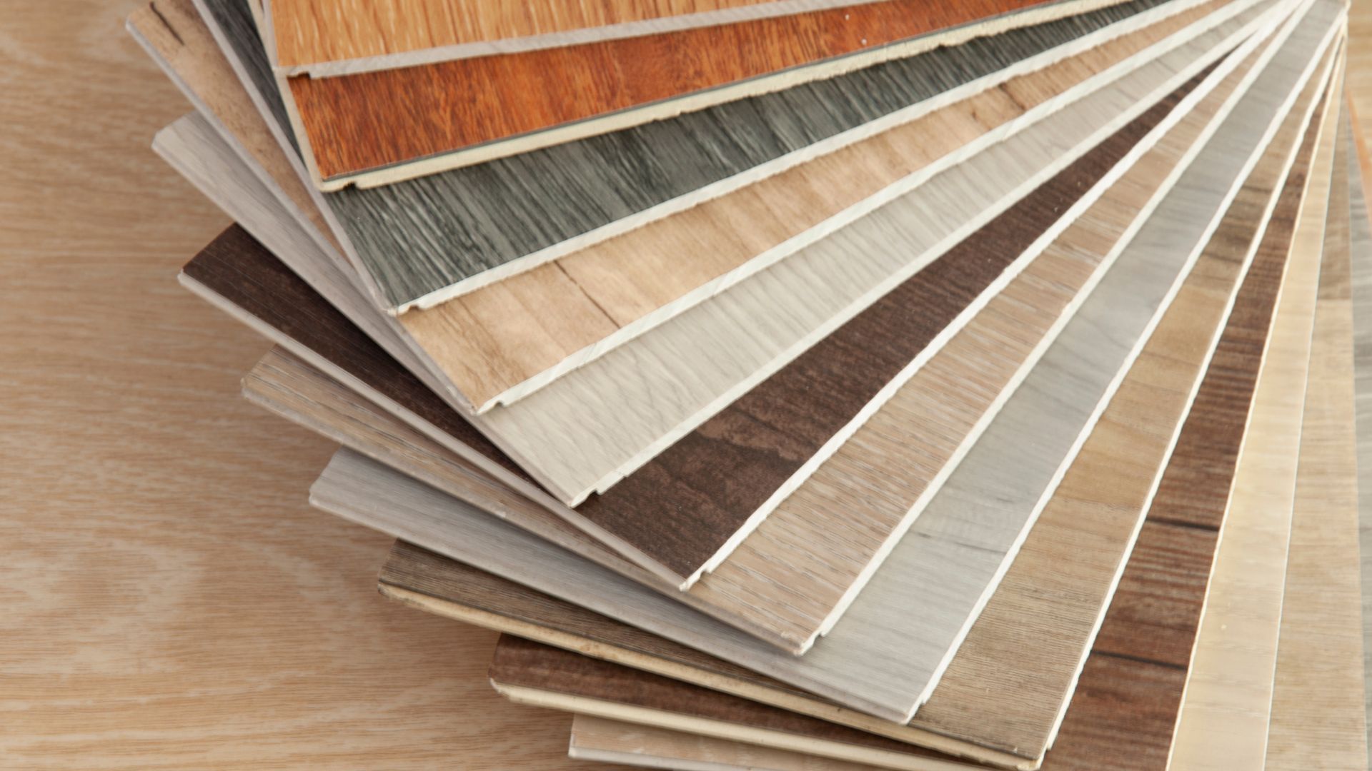 A stack of different types of wooden flooring samples on a wooden table.