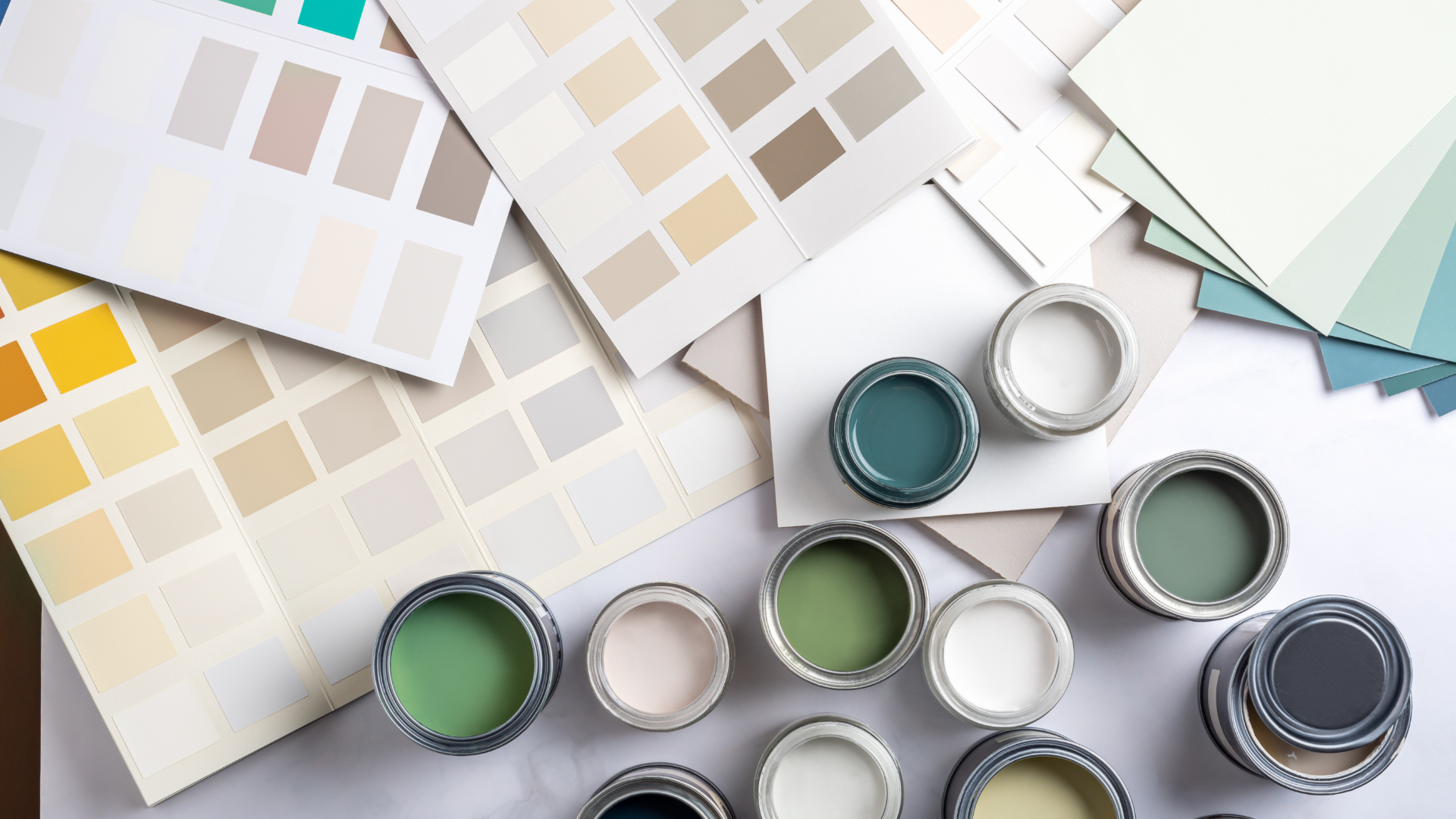 Paint samples and color swatches arranged with small open paint cans in neutral and pastel tones.