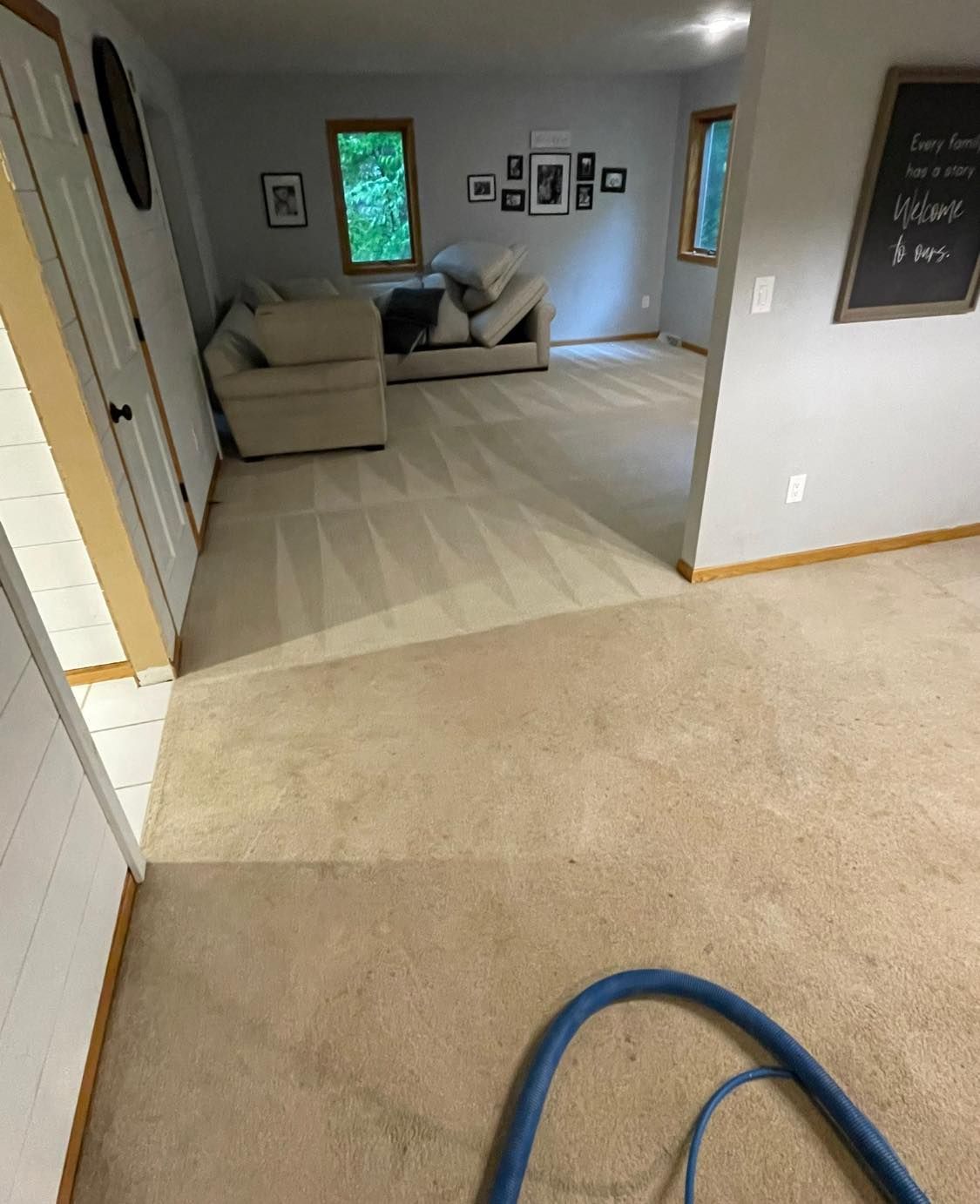 A living room with a couch and chairs and a vacuum hose on the floor.