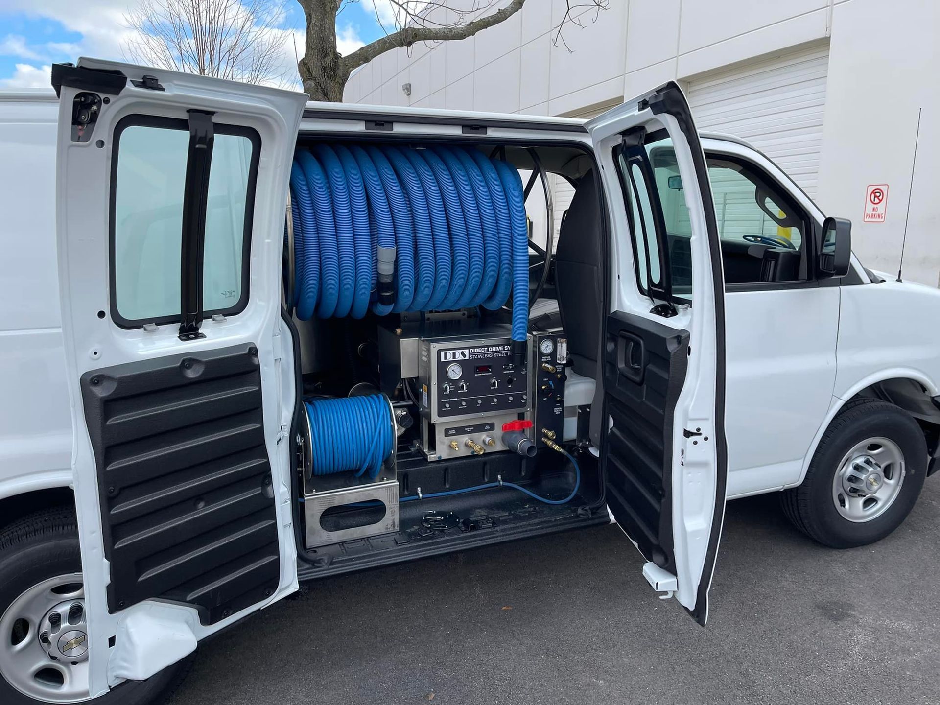 A white van with the door open and a hose in the back.
