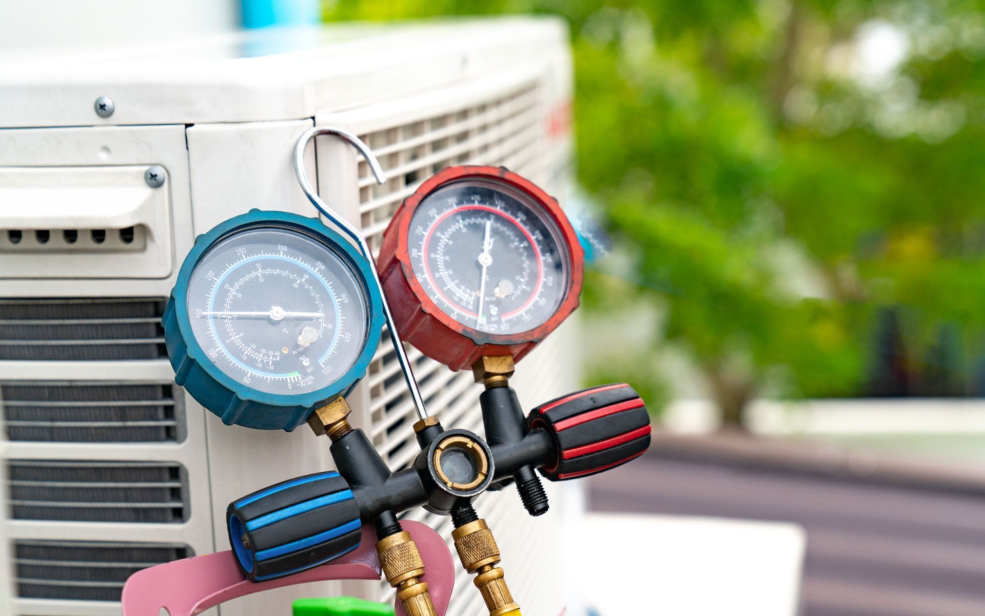 A couple of gauges hanging on a hook next to an air conditioner.