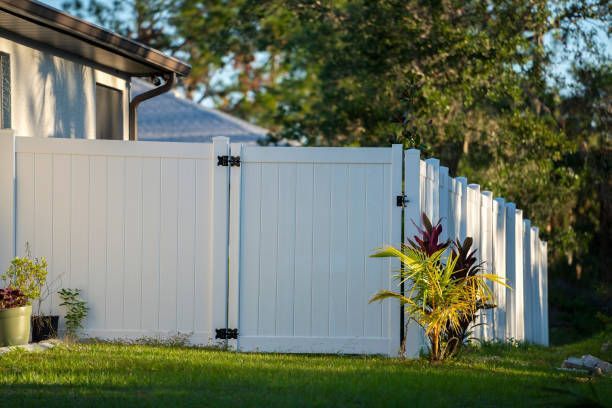 White vinyl fence with gate in a grassy yard. 