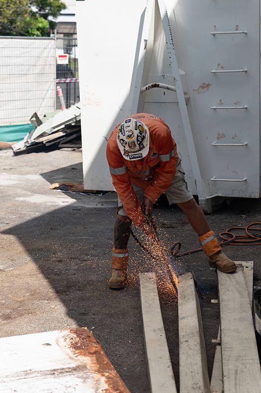 A Man Is Cutting a Piece of Wood with A Saw — Northern Rivers Demolition & Asbestos in Ballina, NSW