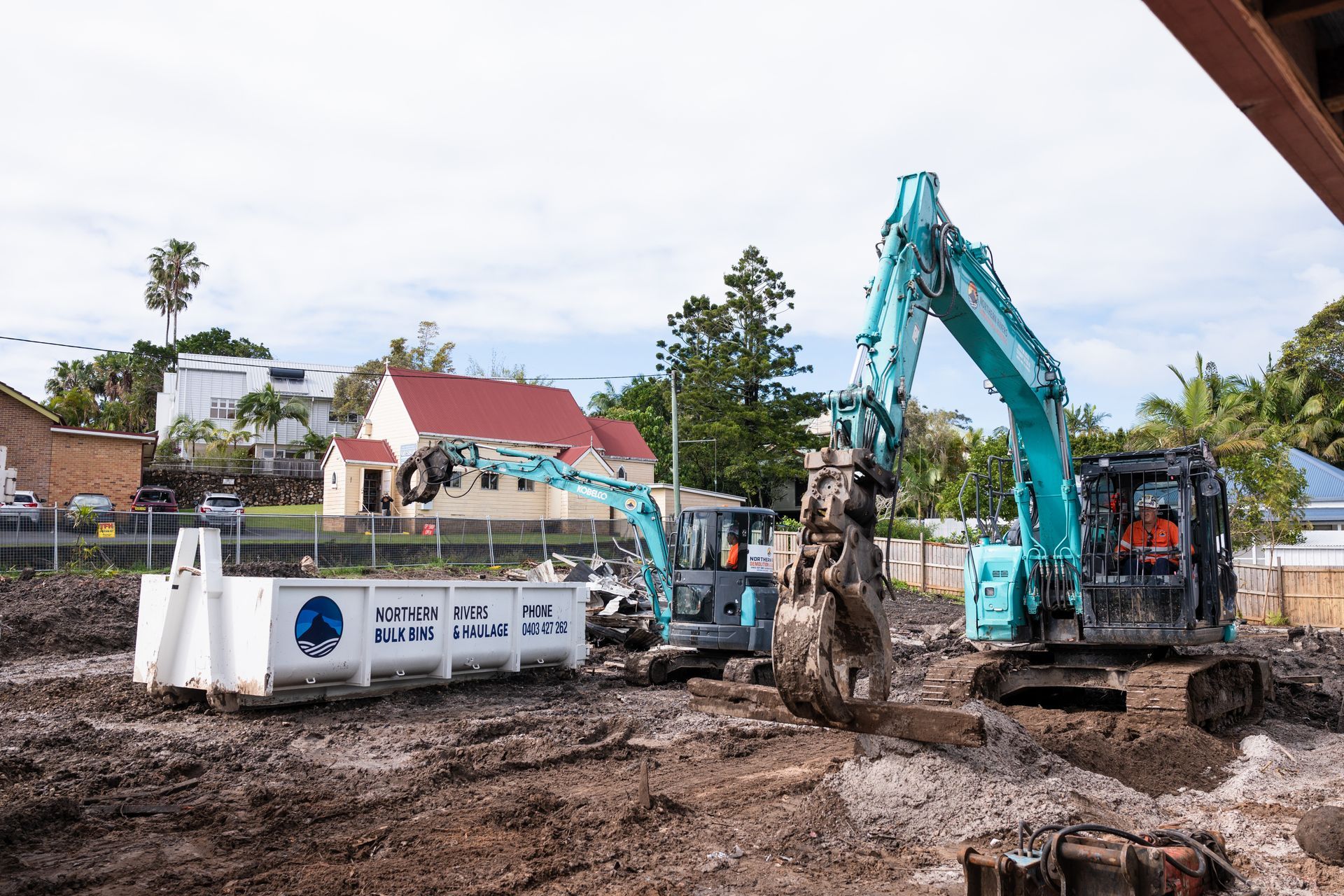 A blue excavator is digging a hole in the dirt.