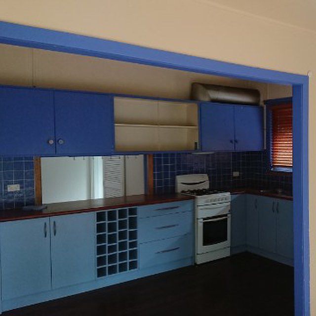 A Kitchen with Blue Cabinets And A White Stove — Northern Rivers Demolition & Asbestos in Skennars Head, NSW