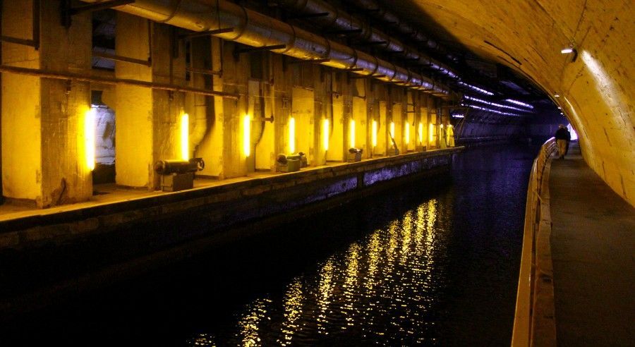 A person is walking through a tunnel next to a body of water.