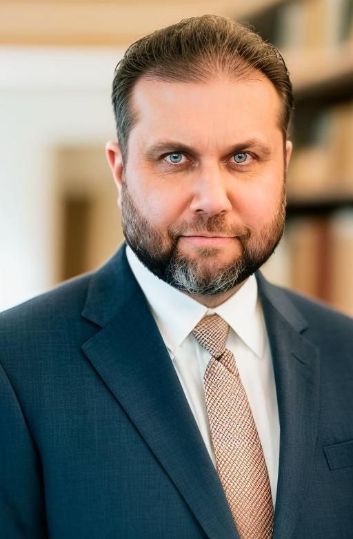 A man with a beard is wearing a suit and tie.