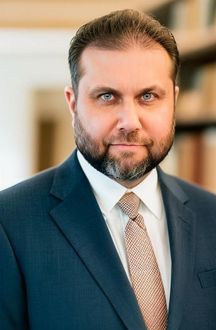 A man with a beard is wearing a suit and tie.