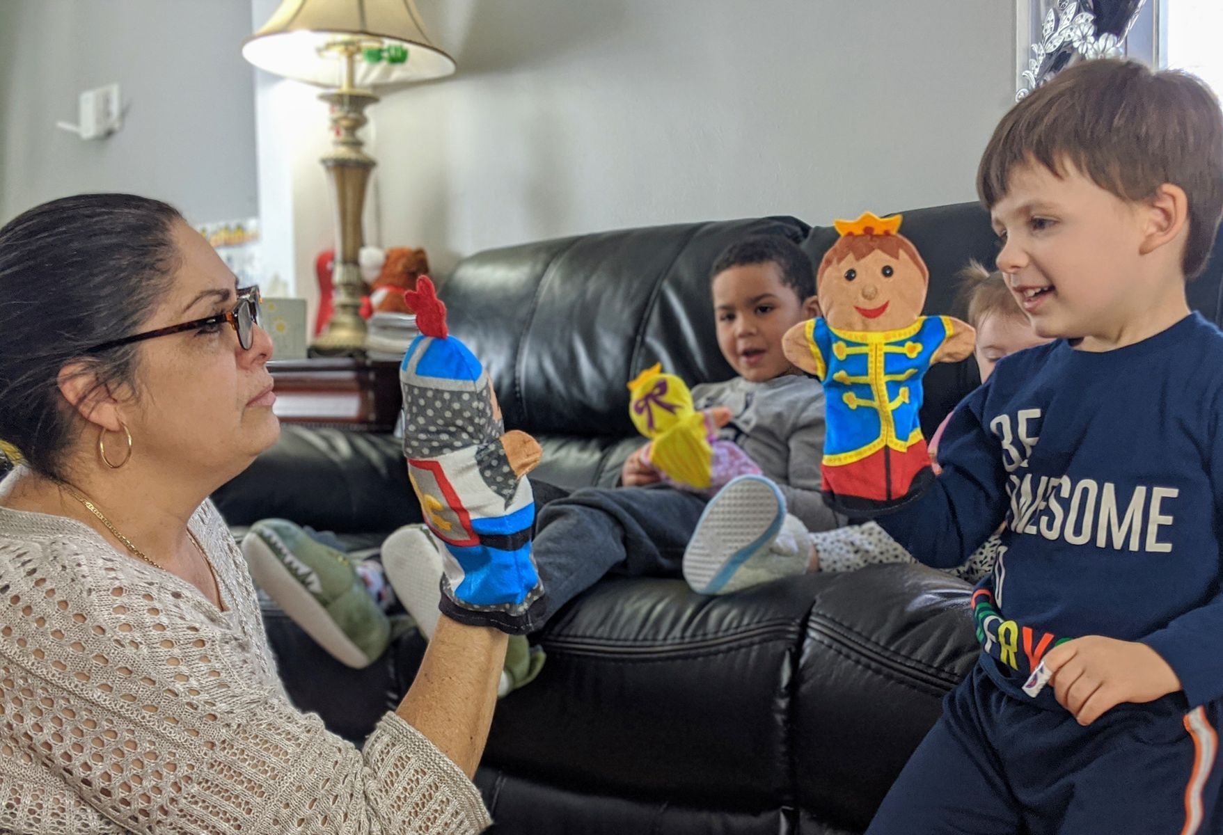 Three babies playing with toys in a room. One reaches for a green toy, another watches, and the last plays with a bead maze.