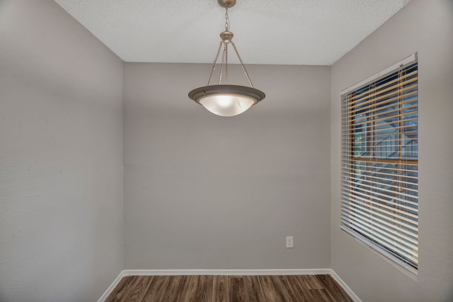 An empty dining room with a chandelier and a window.