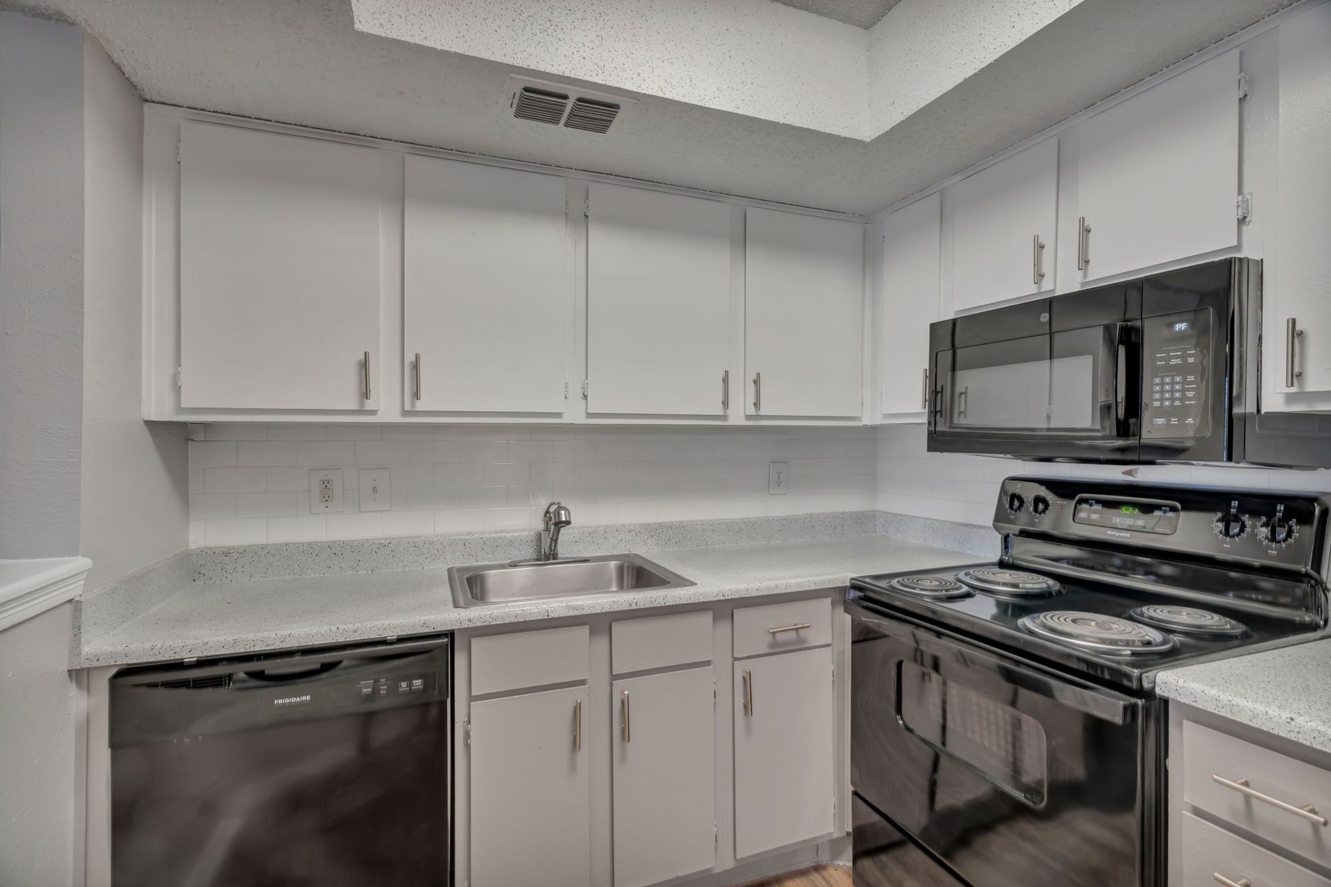 A kitchen with white cabinets , stainless steel appliances , and a sink.