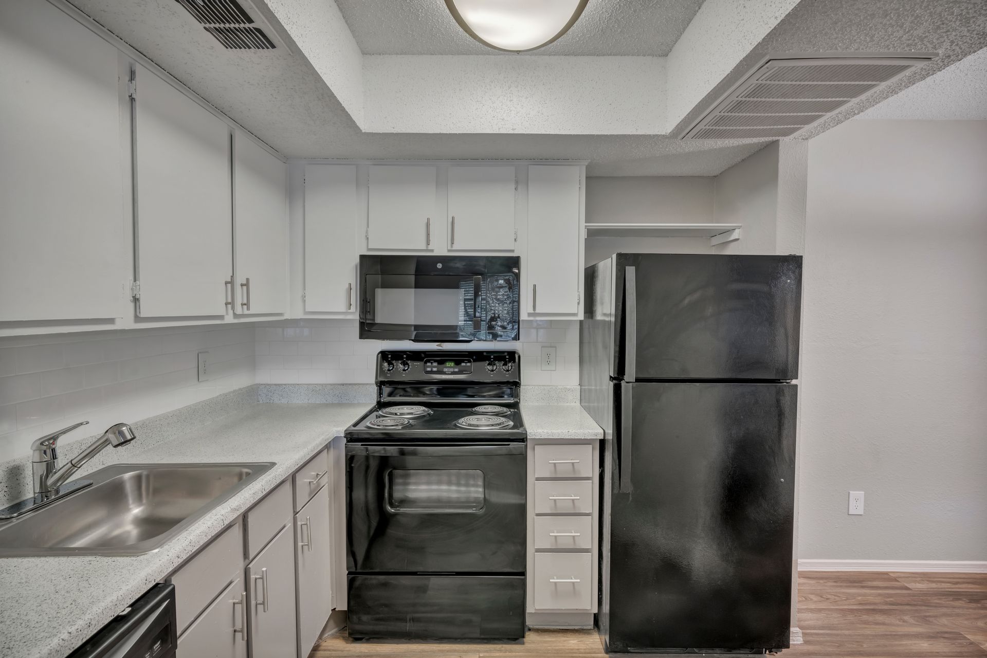 A kitchen with white cabinets and a black refrigerator