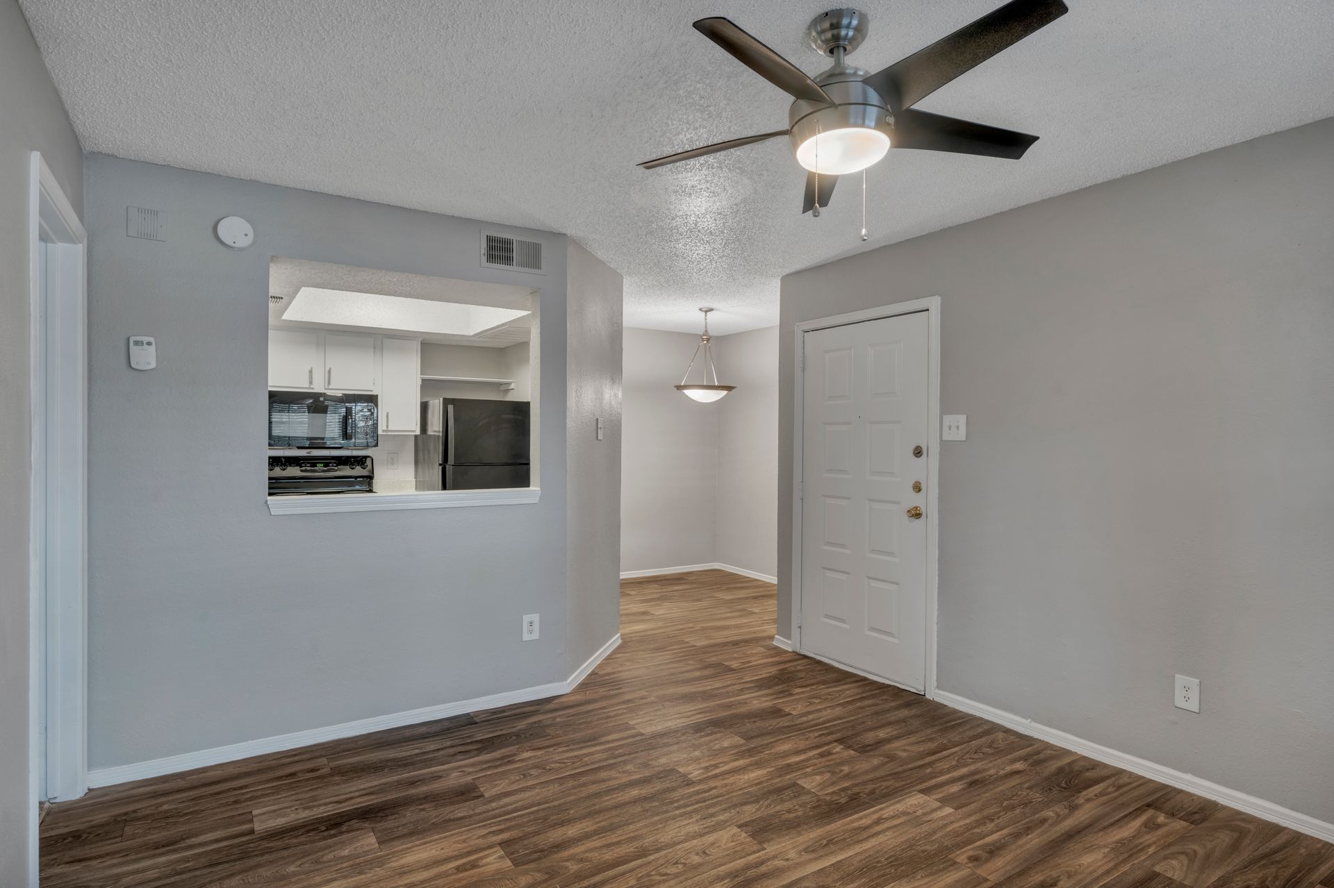 A living room with hardwood floors and a ceiling fan.