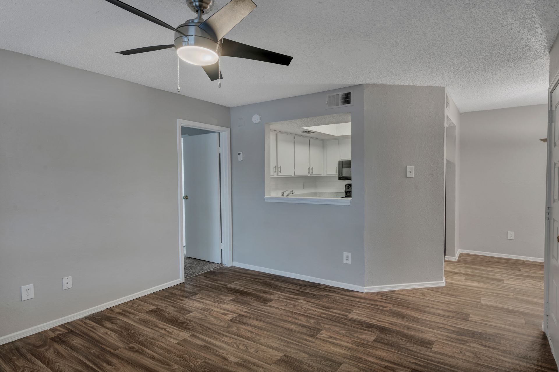 A living room with hardwood floors and a ceiling fan.