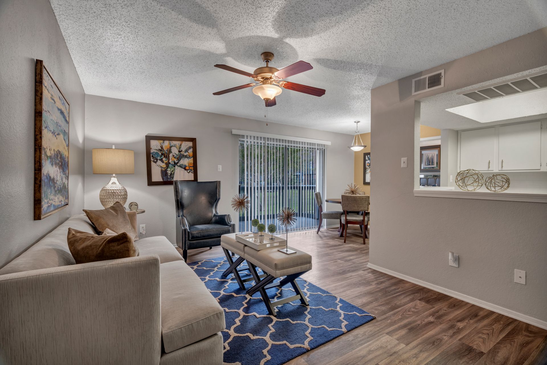 A living room with a couch , chair , coffee table and ceiling fan.