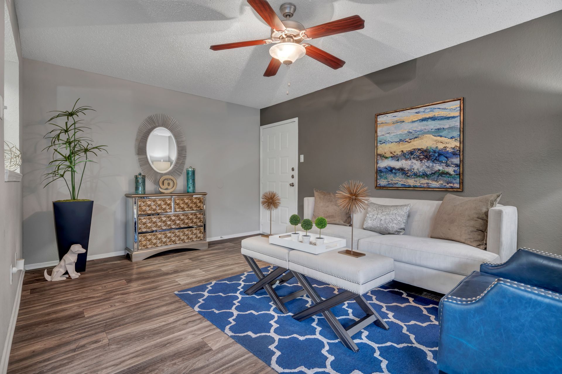 A living room with a couch , coffee table , rug and ceiling fan.