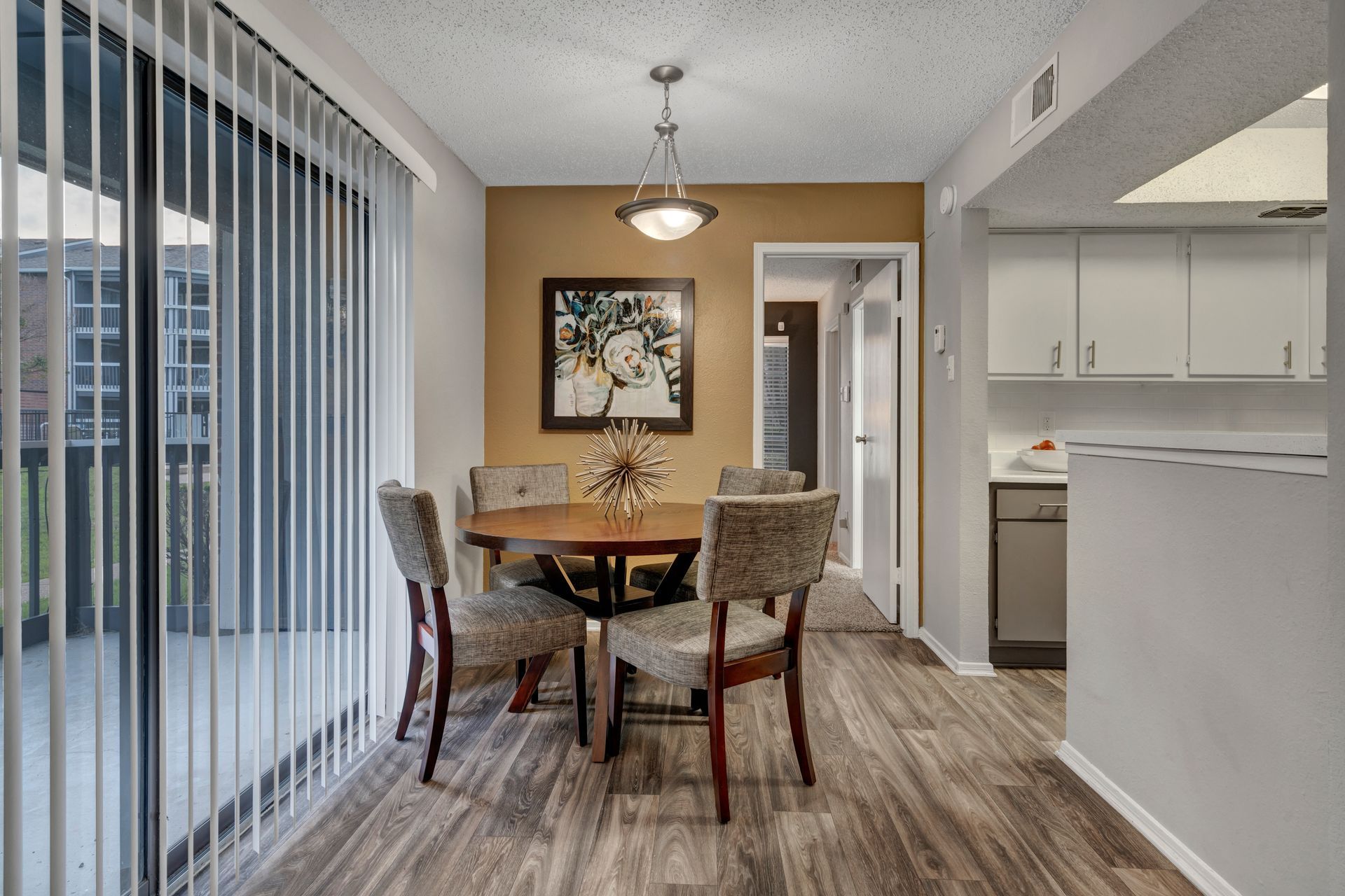 A dining room with a table and chairs and sliding glass doors leading to a balcony.
