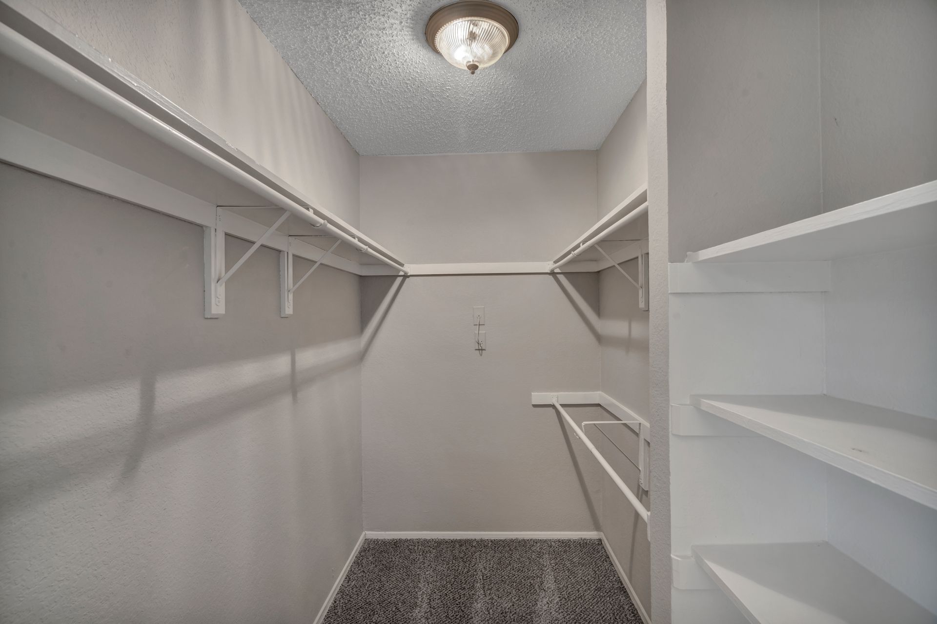 A walk in closet with lots of shelves and a light on the ceiling.