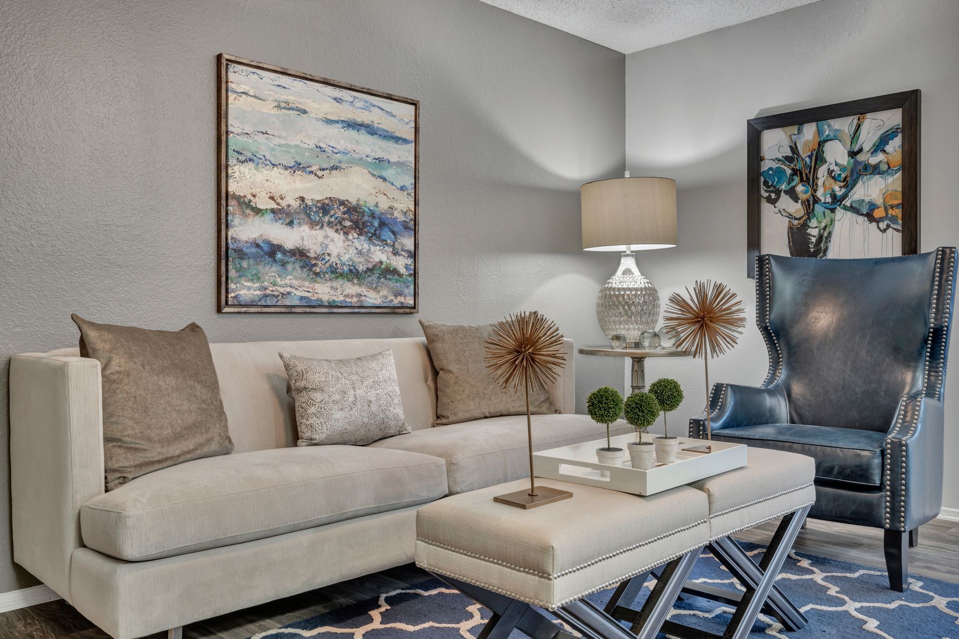 A living room with a couch , chair , coffee table and painting on the wall.