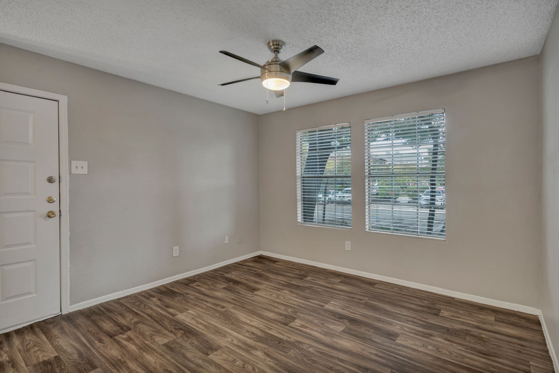An empty room with hardwood floors and a ceiling fan.