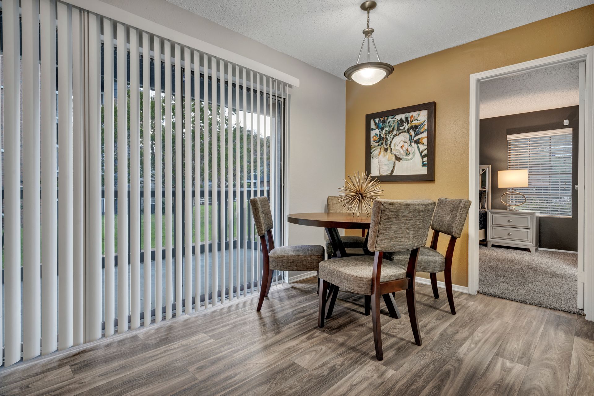 A dining room with a table and chairs and vertical blinds.