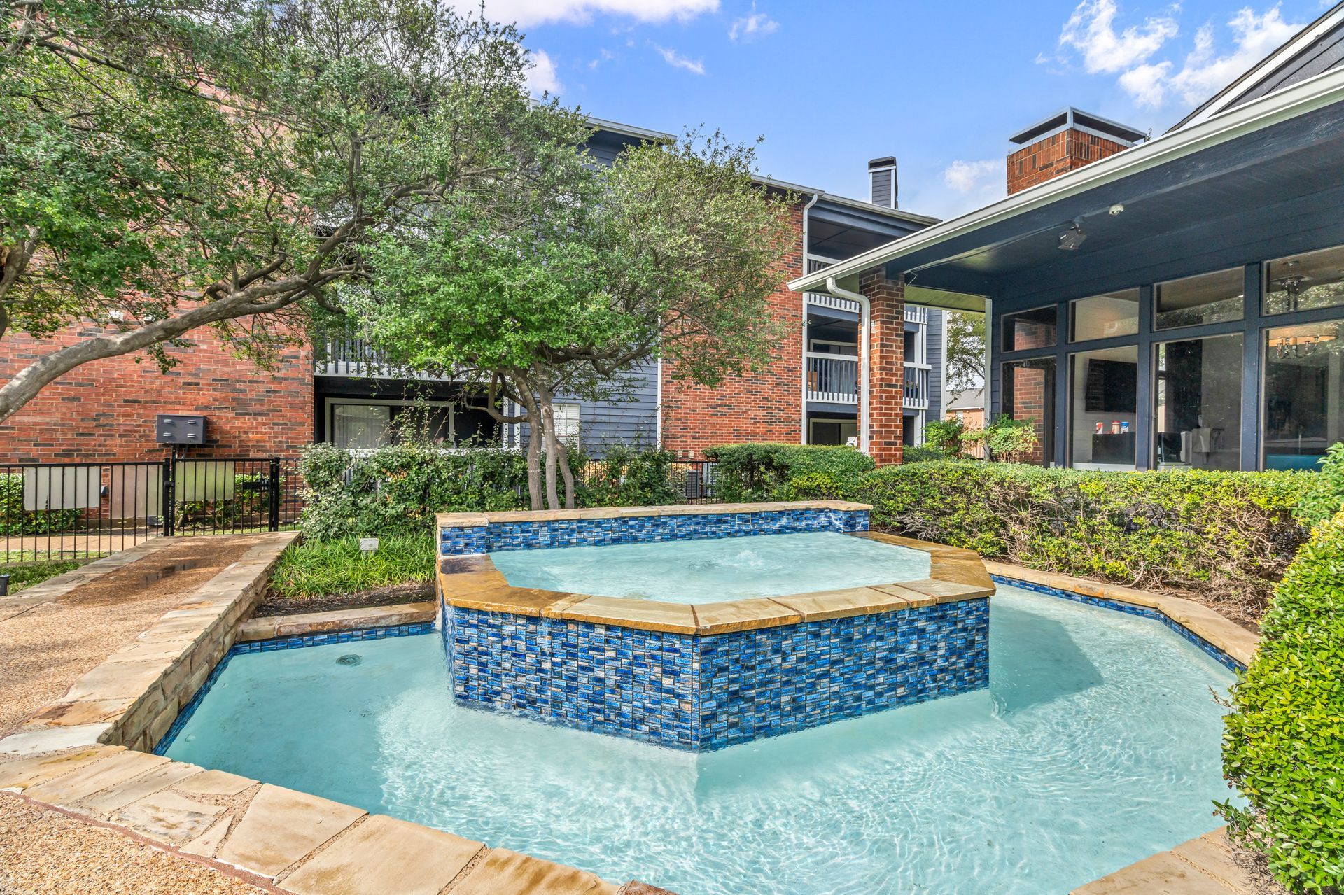 A large swimming pool with a fountain in the middle of it in front of a building.