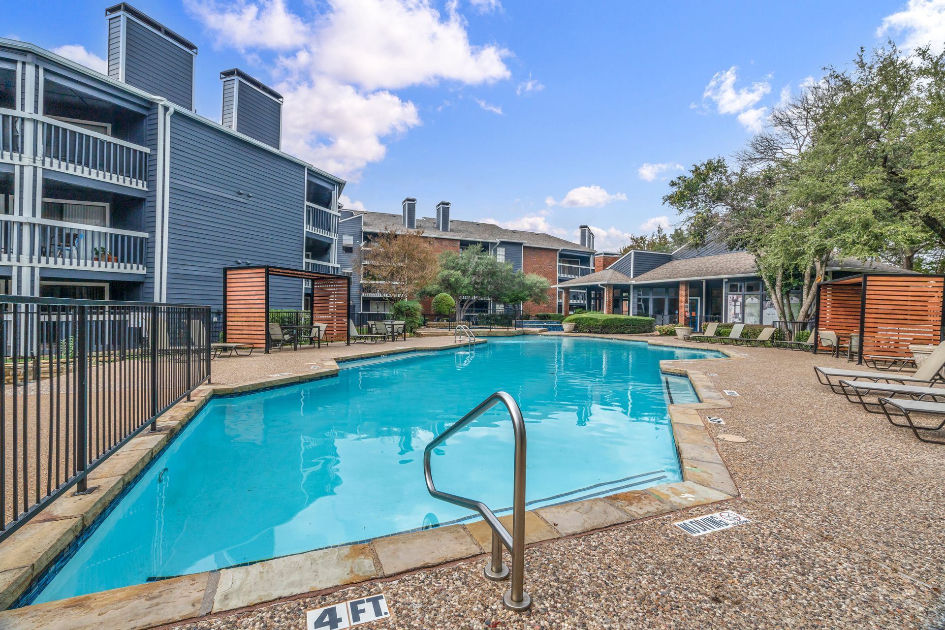 A large swimming pool in front of a building with a fence around it.